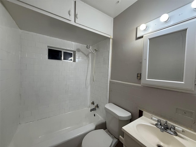 bathroom with toilet, shower / tub combination, vanity, wainscoting, and tile walls