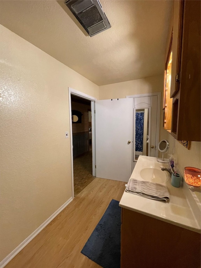 bathroom featuring hardwood / wood-style flooring, vanity, and a textured ceiling