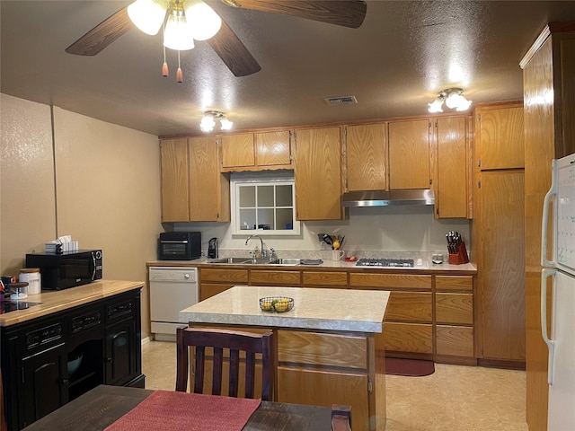 kitchen with sink, a center island, white appliances, ceiling fan, and a textured ceiling