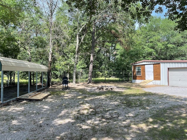 view of yard featuring a carport, a garage, and an outbuilding