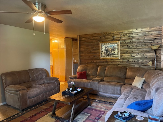 living room featuring ceiling fan and wooden walls