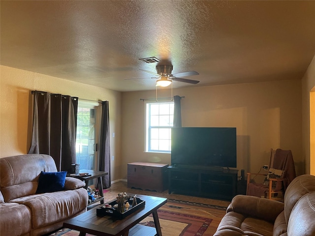 living room featuring ceiling fan, dark hardwood / wood-style flooring, and a textured ceiling