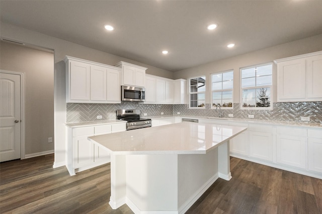 kitchen featuring stainless steel appliances, a kitchen island, sink, and white cabinets