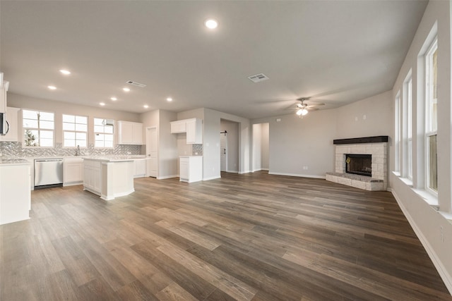 unfurnished living room with ceiling fan, a fireplace, and dark hardwood / wood-style flooring