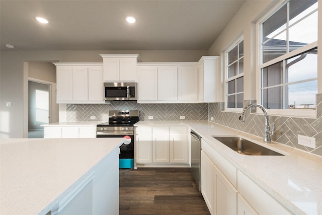 kitchen featuring sink, white cabinets, dark hardwood / wood-style flooring, light stone counters, and stainless steel appliances