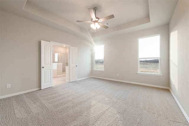 empty room with a tray ceiling, ceiling fan, and carpet