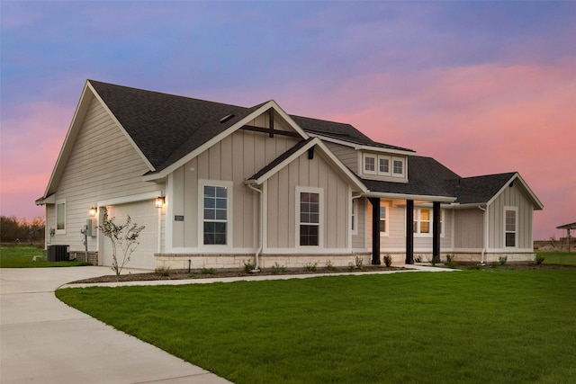 view of front facade featuring a garage, a lawn, and central air condition unit