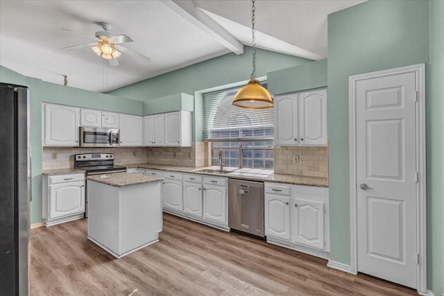 kitchen featuring appliances with stainless steel finishes, white cabinetry, sink, hanging light fixtures, and a center island