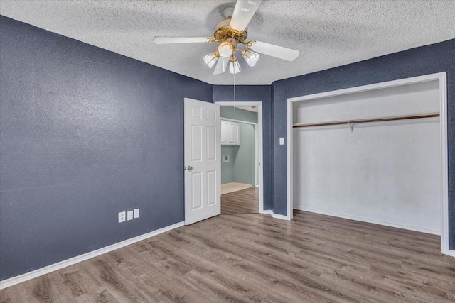 unfurnished bedroom with a textured ceiling, a closet, ceiling fan, and hardwood / wood-style flooring