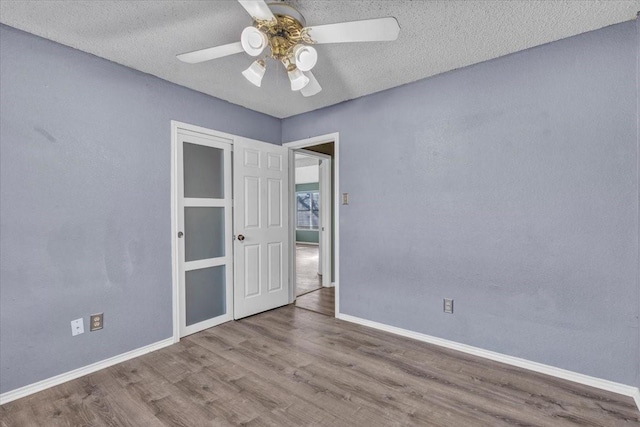 empty room with hardwood / wood-style floors, a textured ceiling, and ceiling fan