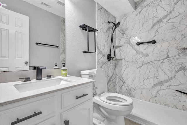 bathroom featuring vanity, tiled shower, a textured ceiling, and toilet