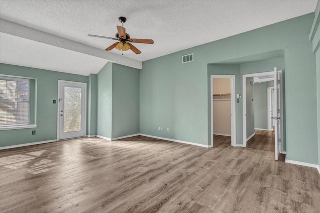 unfurnished living room featuring vaulted ceiling, ceiling fan, light hardwood / wood-style floors, and a textured ceiling