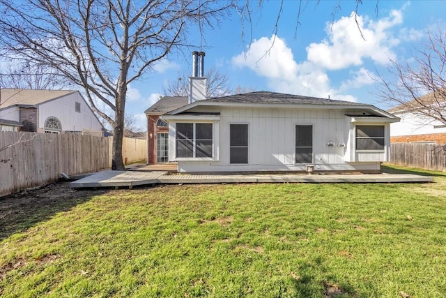 rear view of house featuring a wooden deck, a lawn, and a sunroom