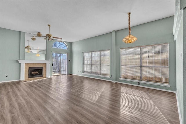 unfurnished living room featuring hardwood / wood-style flooring, ceiling fan, and a tiled fireplace