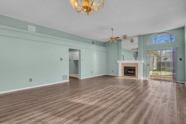 unfurnished living room with wood-type flooring, a fireplace, and ceiling fan with notable chandelier