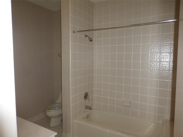 full bathroom with tile patterned flooring, tiled shower / bath, vanity, and toilet