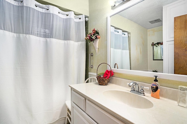 bathroom with vanity, a textured ceiling, and walk in shower