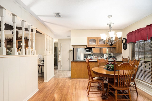 dining room featuring an inviting chandelier, ornamental molding, and light wood-type flooring