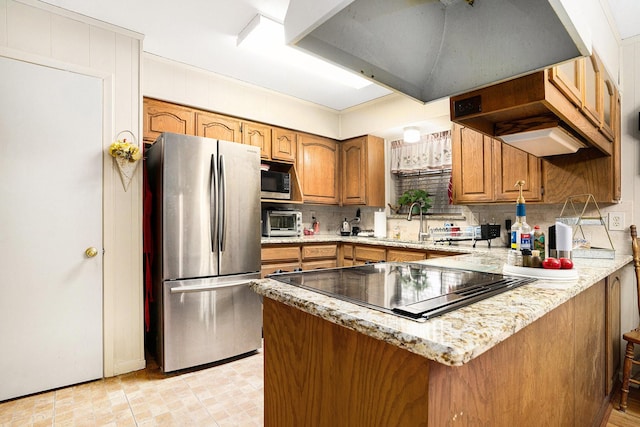 kitchen featuring stainless steel refrigerator, black electric cooktop, kitchen peninsula, and sink