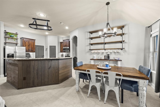 kitchen with stainless steel appliances, a notable chandelier, dark brown cabinetry, and decorative light fixtures