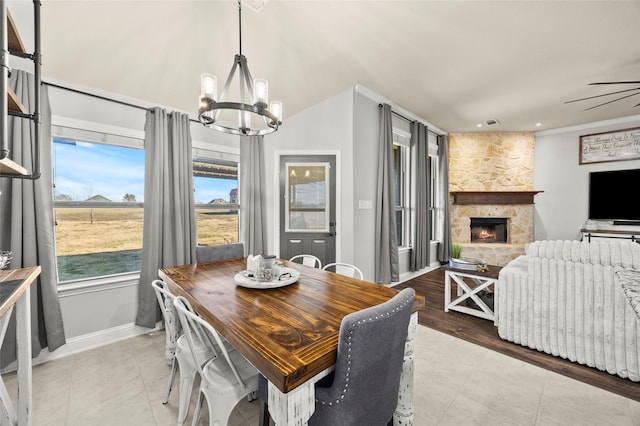 dining area featuring crown molding, a notable chandelier, and a stone fireplace