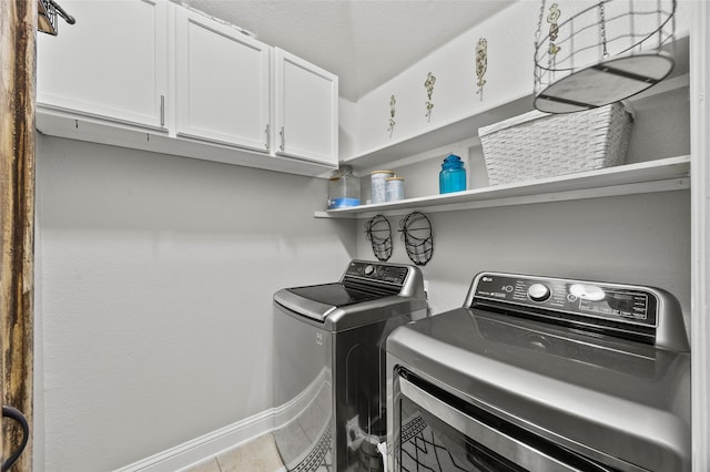 laundry room with independent washer and dryer, light tile patterned floors, and cabinets