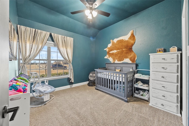 bedroom with a crib, vaulted ceiling, carpet flooring, and ceiling fan