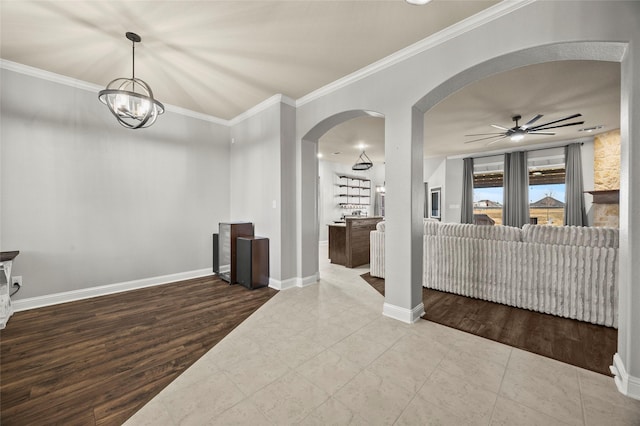 interior space with crown molding, ceiling fan with notable chandelier, and hardwood / wood-style flooring