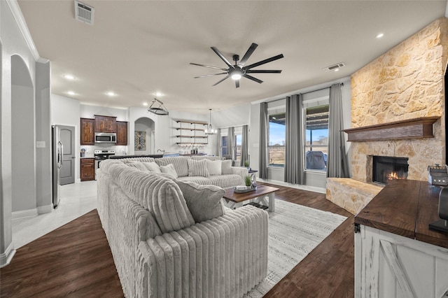 living room with ceiling fan, a stone fireplace, and hardwood / wood-style floors