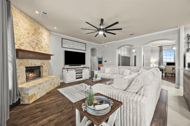 living room with hardwood / wood-style floors, a fireplace, ornamental molding, and ceiling fan