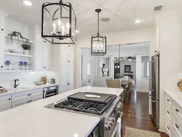 kitchen with pendant lighting, white cabinetry, beverage cooler, stainless steel appliances, and crown molding