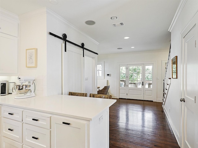 kitchen featuring dark hardwood / wood-style floors, white cabinetry, kitchen peninsula, crown molding, and a barn door