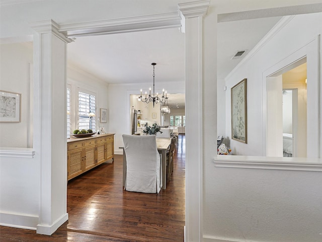 dining room with crown molding, dark wood-type flooring, and ornate columns