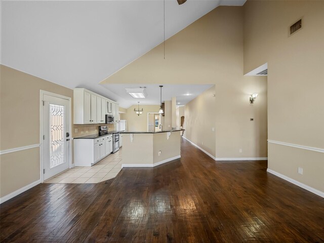 kitchen with lofted ceiling, sink, white cabinetry, tasteful backsplash, and appliances with stainless steel finishes