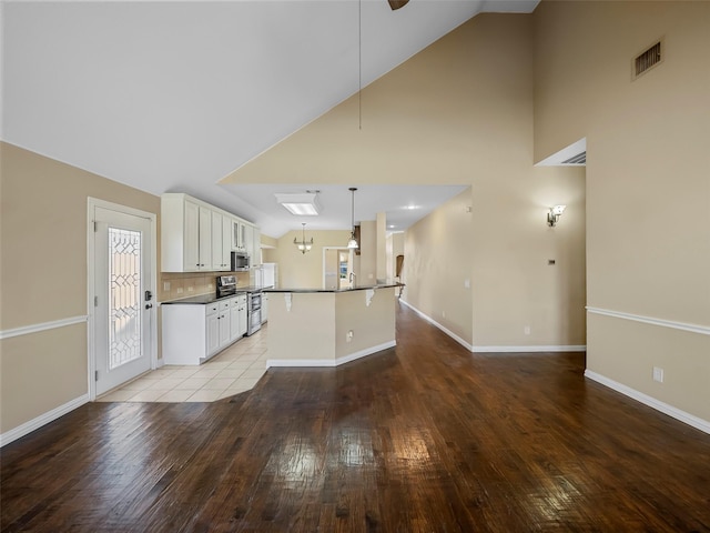 kitchen featuring appliances with stainless steel finishes, pendant lighting, white cabinets, a center island with sink, and light wood-type flooring