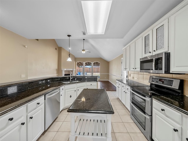 kitchen with sink, stainless steel appliances, a center island, white cabinets, and decorative light fixtures