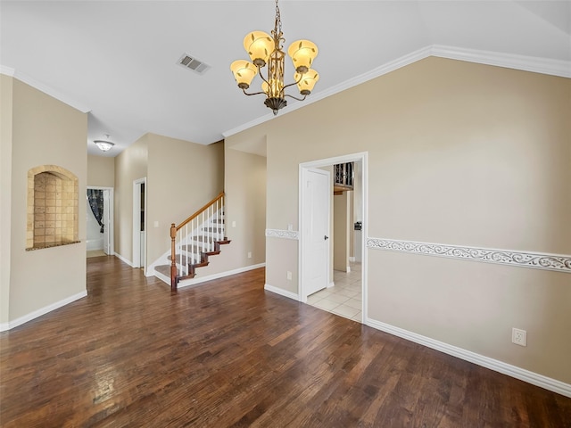 spare room with wood-type flooring, lofted ceiling, ornamental molding, and a chandelier