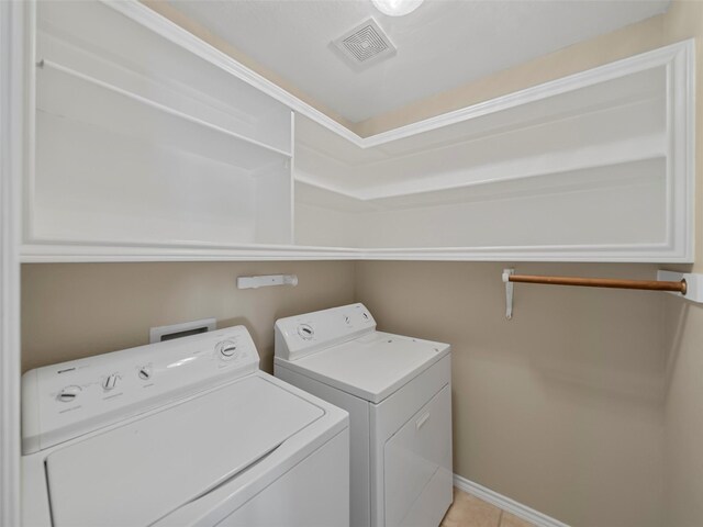 laundry area with light tile patterned floors, cabinets, and washing machine and clothes dryer