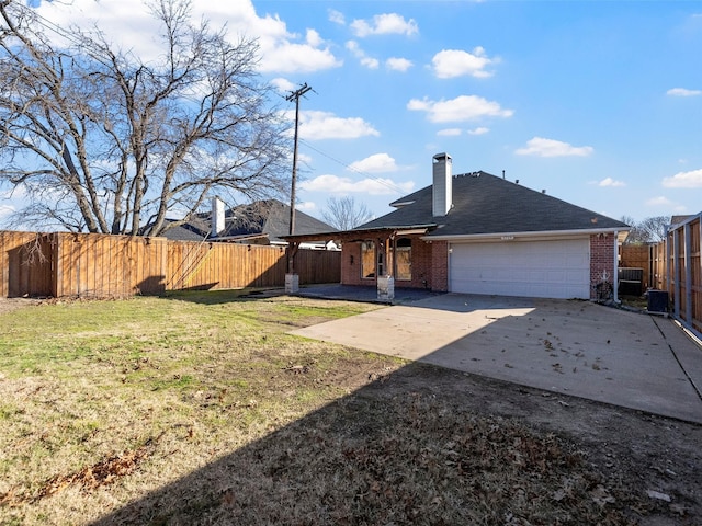 back of house with central AC unit, a garage, and a lawn