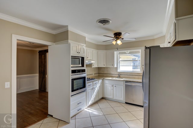 kitchen with white cabinetry, ornamental molding, light tile patterned floors, ceiling fan, and stainless steel appliances