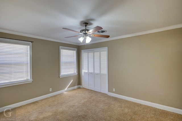 carpeted empty room with ceiling fan, ornamental molding, and a healthy amount of sunlight