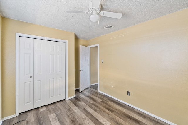 unfurnished bedroom featuring wood-type flooring, a textured ceiling, ceiling fan, and a closet