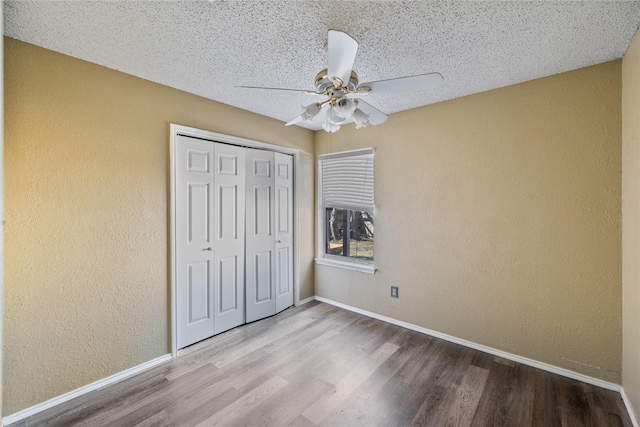 unfurnished bedroom featuring a textured ceiling, a closet, ceiling fan, and light wood-type flooring