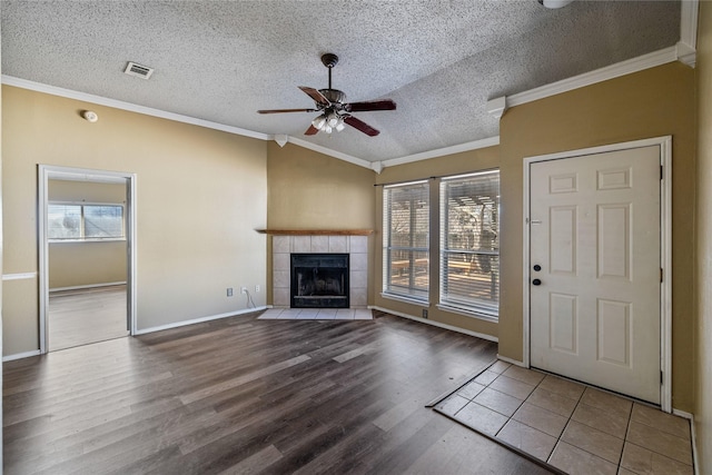 unfurnished living room with a tiled fireplace, ornamental molding, a textured ceiling, and lofted ceiling