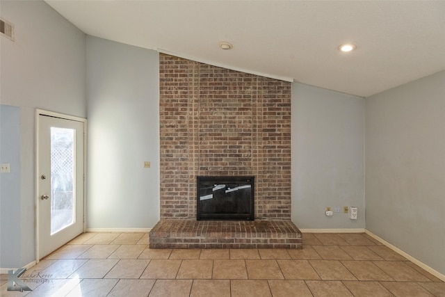 unfurnished living room featuring vaulted ceiling, a brick fireplace, and light tile patterned floors