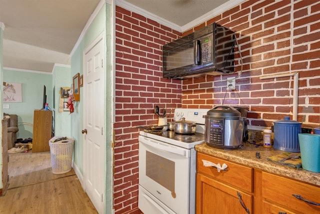 kitchen featuring electric stove, brick wall, light hardwood / wood-style floors, and light stone counters