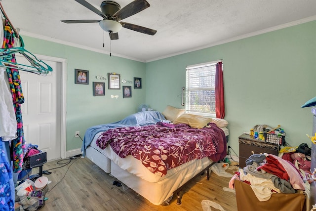 bedroom with ornamental molding, light wood-type flooring, and ceiling fan