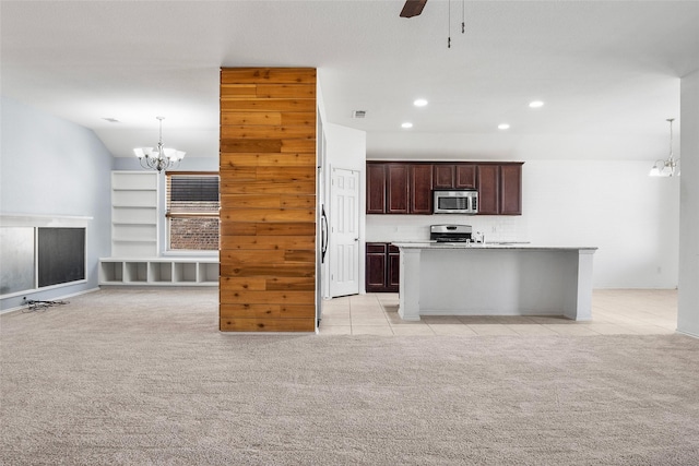 kitchen with light colored carpet, appliances with stainless steel finishes, an island with sink, and hanging light fixtures