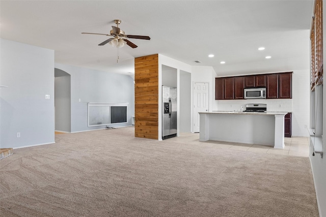 unfurnished living room featuring recessed lighting, arched walkways, light colored carpet, and a ceiling fan