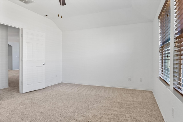 carpeted spare room with visible vents, a ceiling fan, and vaulted ceiling